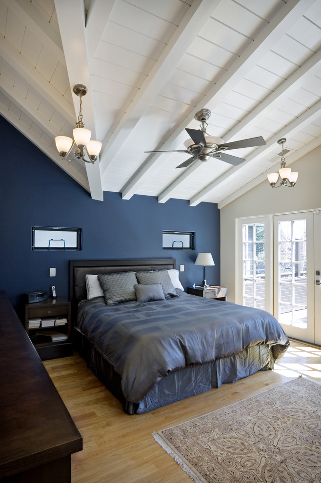 Diseño de dormitorio tradicional sin chimenea con suelo de madera clara y paredes azules