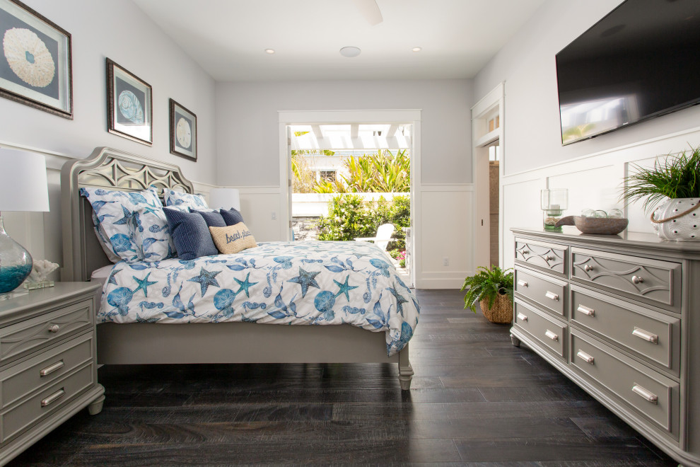 Example of a beach style master dark wood floor, brown floor and wall paneling bedroom design in Orange County with gray walls and no fireplace