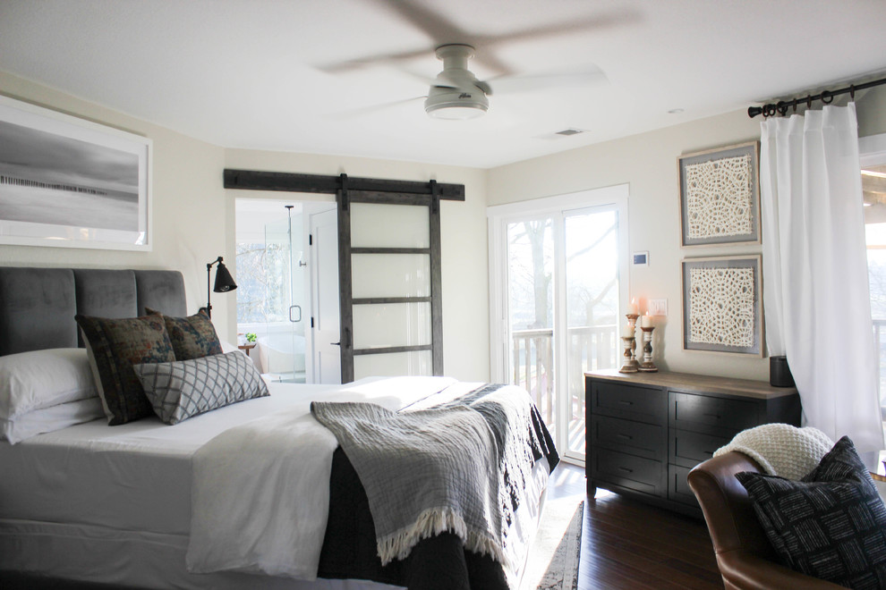 Cette image montre une chambre parentale minimaliste de taille moyenne avec un mur gris, parquet foncé, cheminée suspendue, un manteau de cheminée en bois et un sol marron.