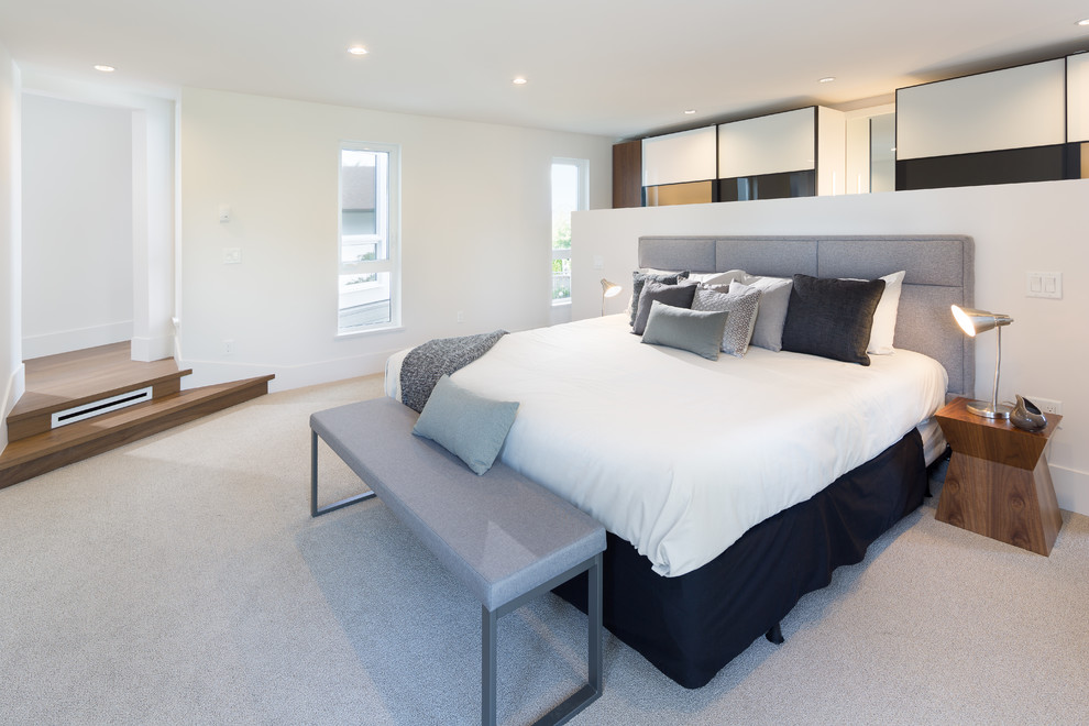 Medium sized modern master bedroom with white walls, carpet and beige floors.