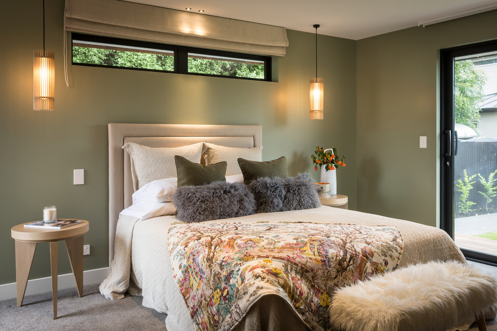 Large modern master bedroom in Christchurch with green walls, carpet and grey floors.
