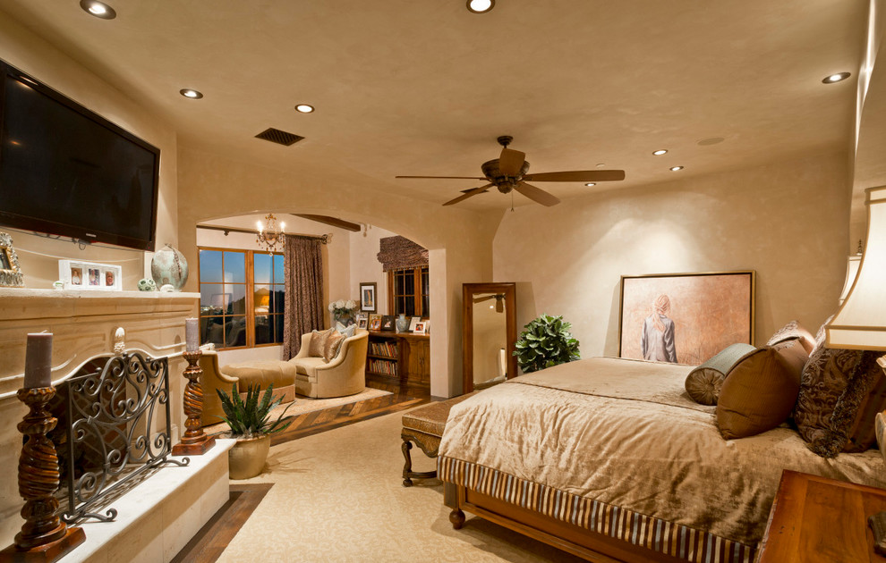 フェニックスにある巨大なサンタフェスタイルのおしゃれな主寝室 (ベージュの壁、カーペット敷き、標準型暖炉、石材の暖炉まわり) のレイアウト