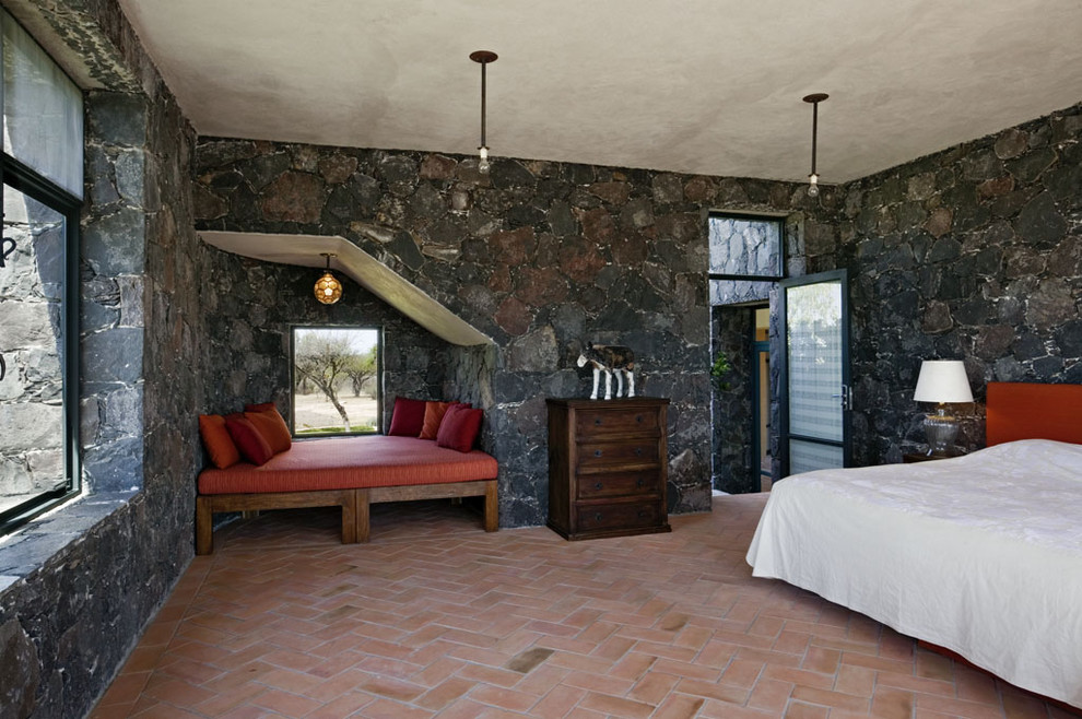 ニューヨークにある地中海スタイルのおしゃれな寝室 (レンガの床、グレーの壁) のインテリア