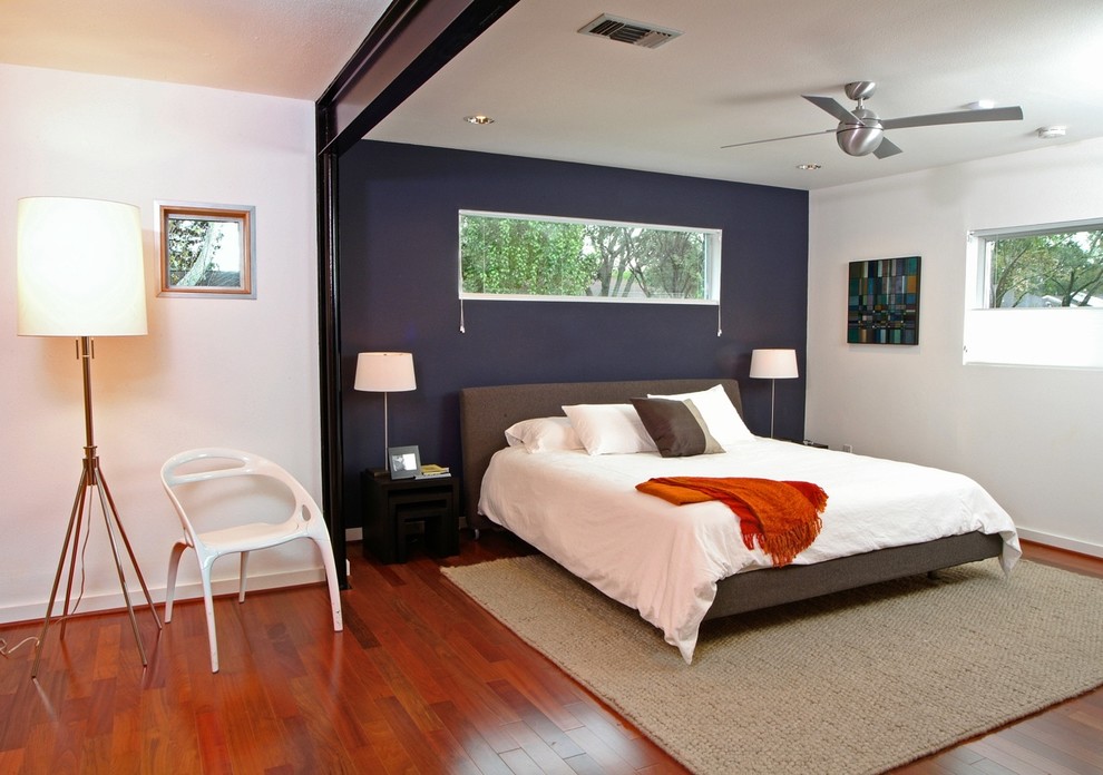 Modernes Schlafzimmer mit blauer Wandfarbe, braunem Holzboden und orangem Boden in Houston