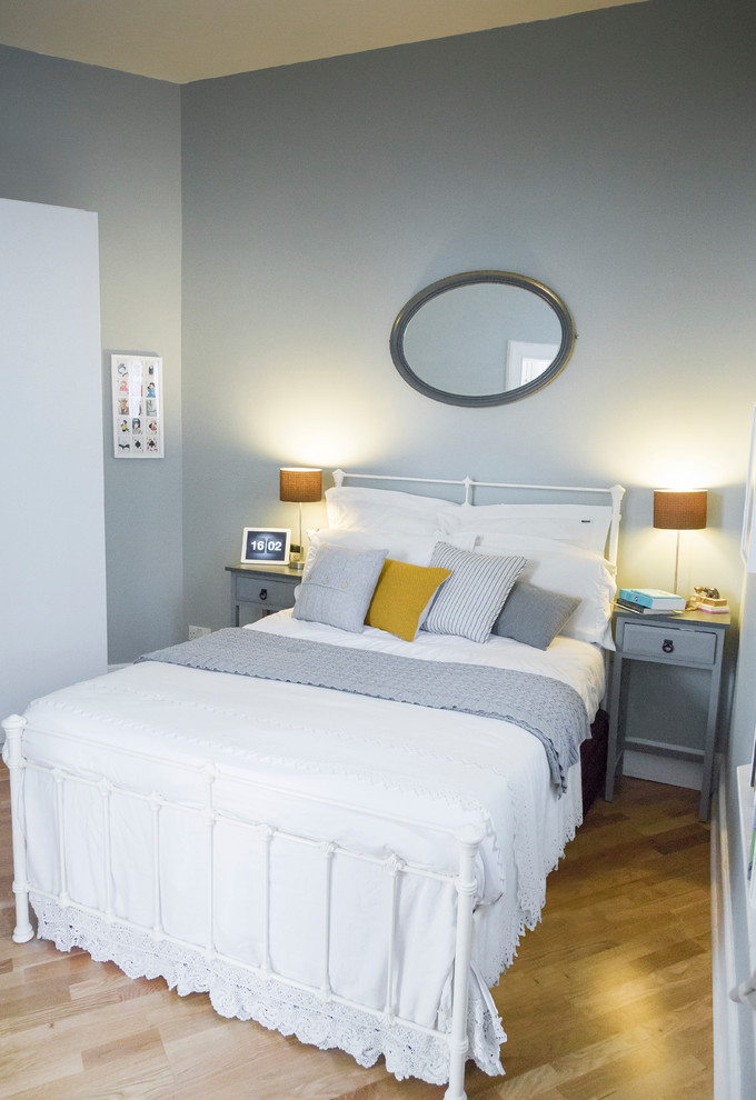 Imagen de dormitorio principal contemporáneo pequeño sin chimenea con paredes azules y suelo de madera en tonos medios