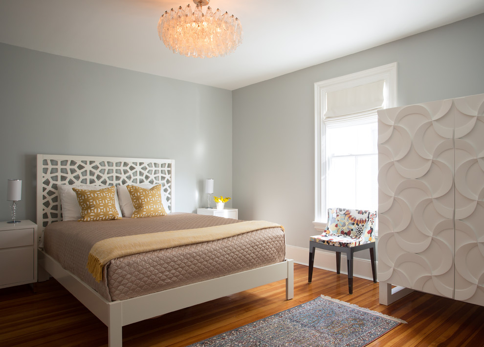 Immagine di una camera degli ospiti design di medie dimensioni con pareti grigie, pavimento in legno massello medio e nessun camino