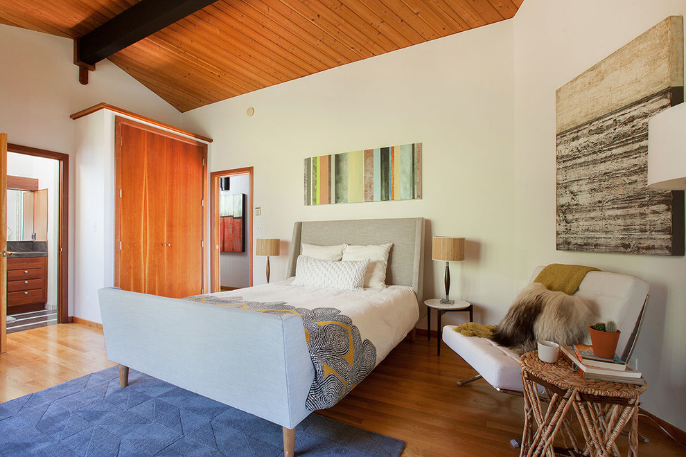 Ejemplo de dormitorio principal retro grande con paredes blancas y suelo de madera en tonos medios