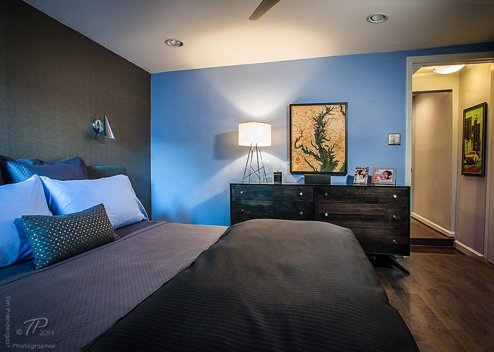 Modelo de dormitorio principal retro de tamaño medio sin chimenea con paredes azules y suelo de madera oscura