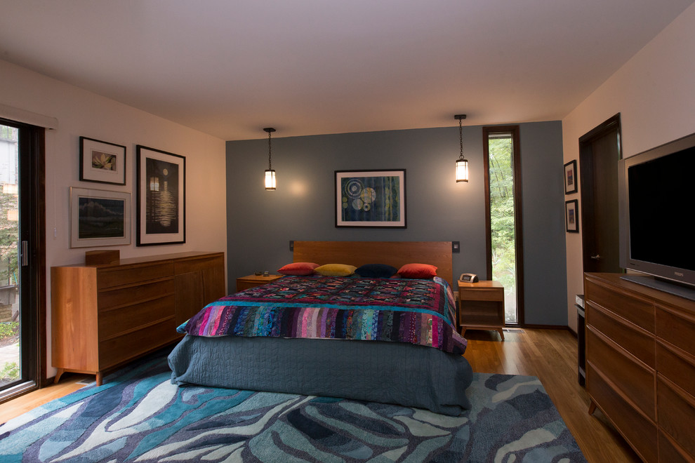 На фото: большая хозяйская спальня в стиле фьюжн с разноцветными стенами, паркетным полом среднего тона и оранжевым полом