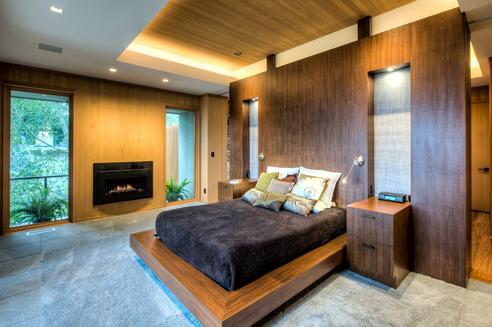 Bedroom - large mid-century modern guest carpeted and gray floor bedroom idea in San Francisco with brown walls, a standard fireplace and a wood fireplace surround
