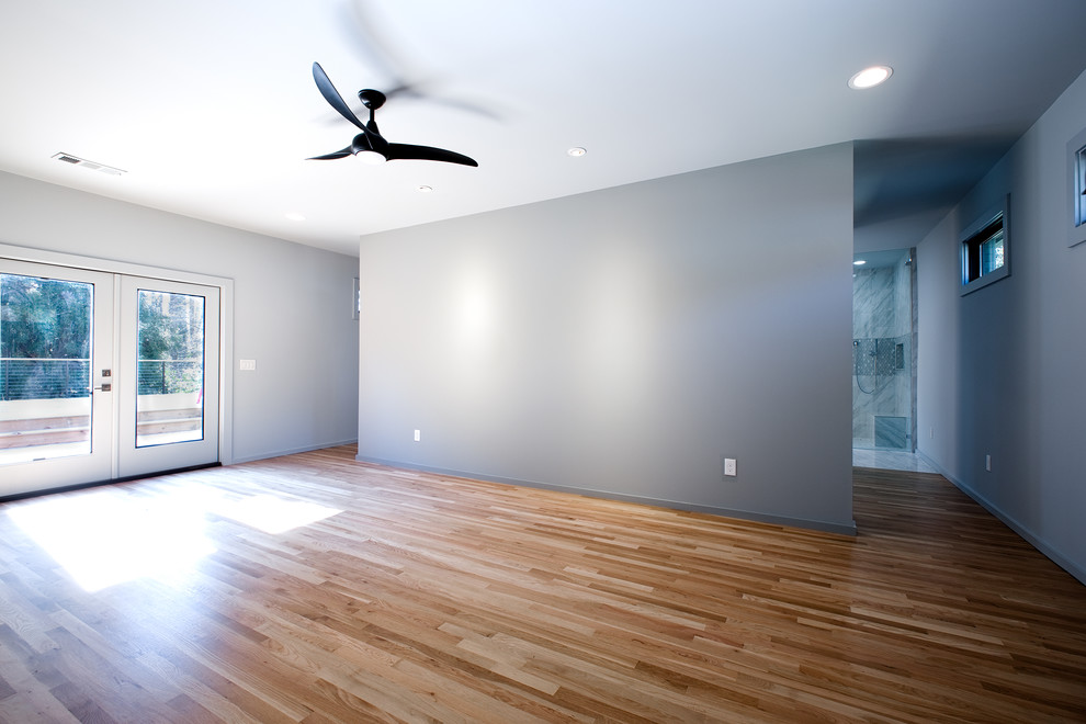 Modern inredning av ett mellanstort huvudsovrum, med grå väggar, ljust trägolv och brunt golv