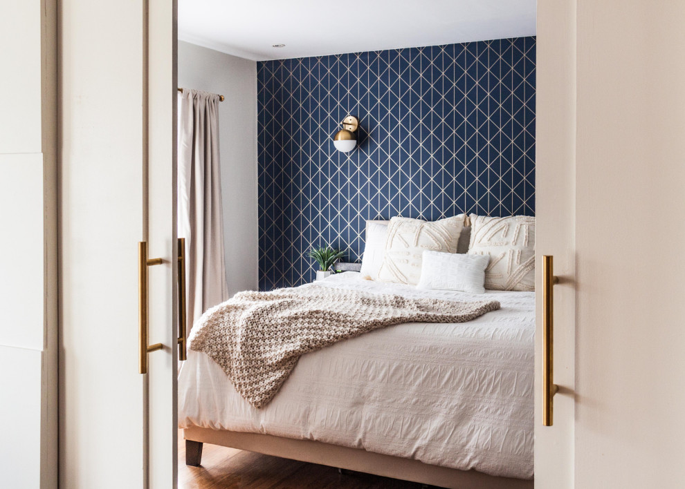 Ejemplo de dormitorio principal vintage de tamaño medio con paredes azules, suelo de madera en tonos medios, suelo marrón y papel pintado