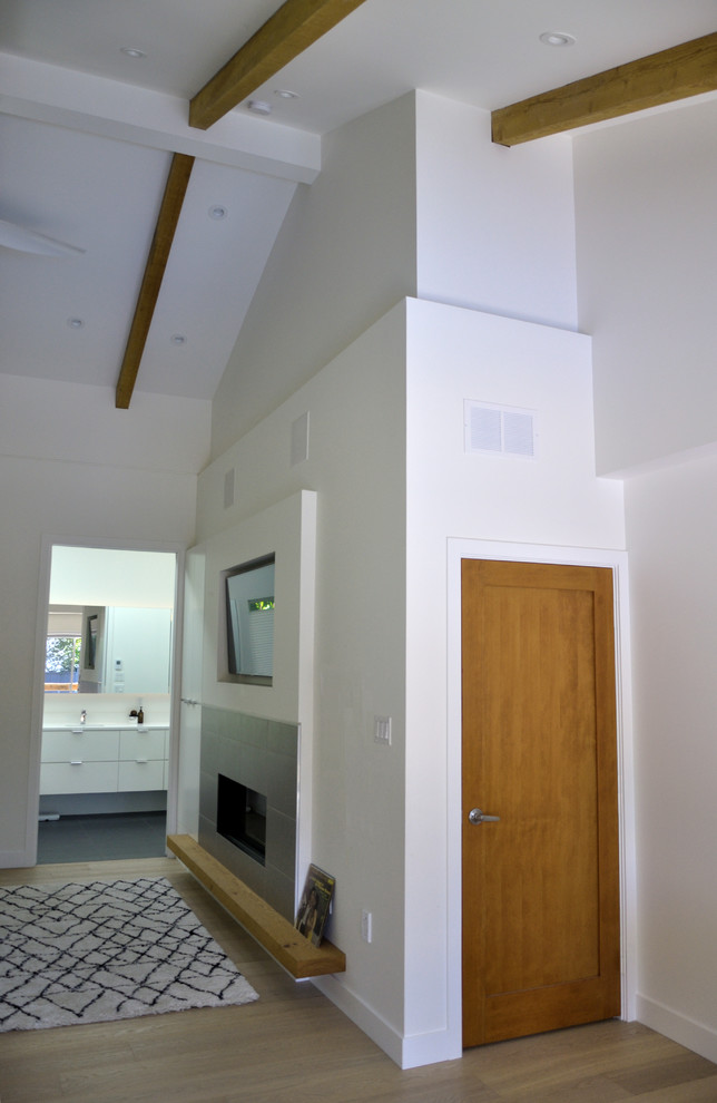 バンクーバーにある中くらいなミッドセンチュリースタイルのおしゃれな主寝室 (白い壁、淡色無垢フローリング、横長型暖炉、タイルの暖炉まわり、茶色い床)
