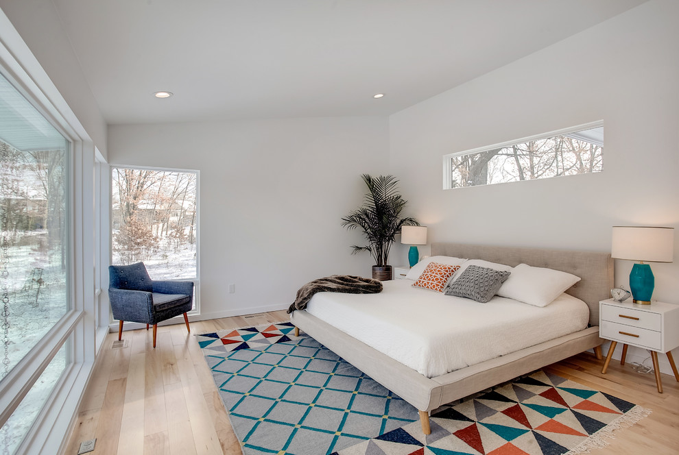 Foto de dormitorio principal retro de tamaño medio sin chimenea con paredes blancas, suelo de madera clara y suelo beige