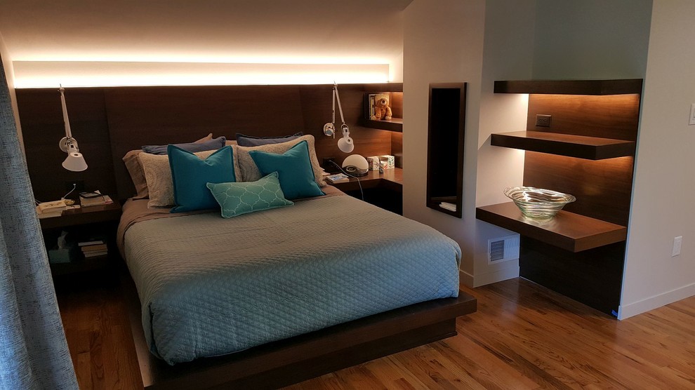 Modelo de dormitorio principal retro sin chimenea con paredes grises, suelo de madera en tonos medios y suelo marrón
