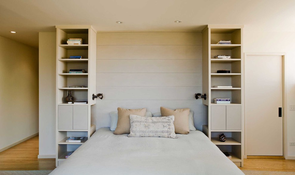 Modelo de dormitorio principal moderno grande con paredes beige y suelo de madera en tonos medios