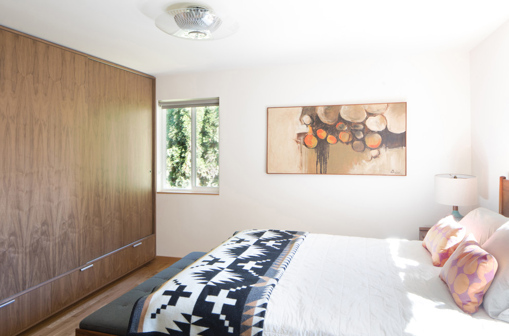 Ejemplo de dormitorio principal retro de tamaño medio con paredes blancas y suelo de madera en tonos medios