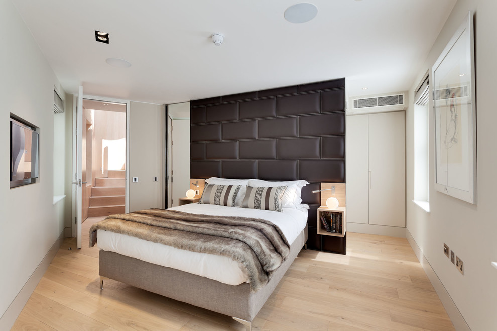 Design ideas for a small contemporary guest bedroom in London with light hardwood flooring and white walls.