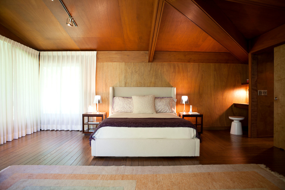 Large retro master bedroom in New York with brown walls and medium hardwood flooring.