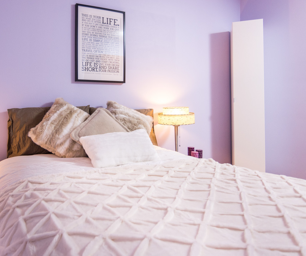 Foto de dormitorio minimalista de tamaño medio sin chimenea con paredes púrpuras y suelo de madera en tonos medios