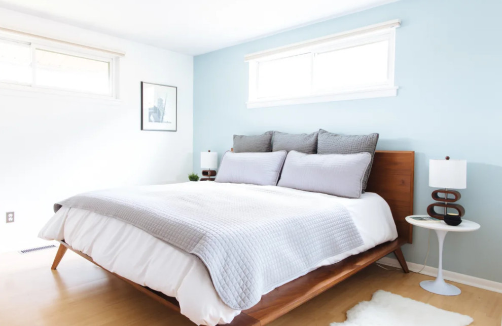 Diseño de dormitorio principal retro de tamaño medio con paredes azules y suelo de madera clara