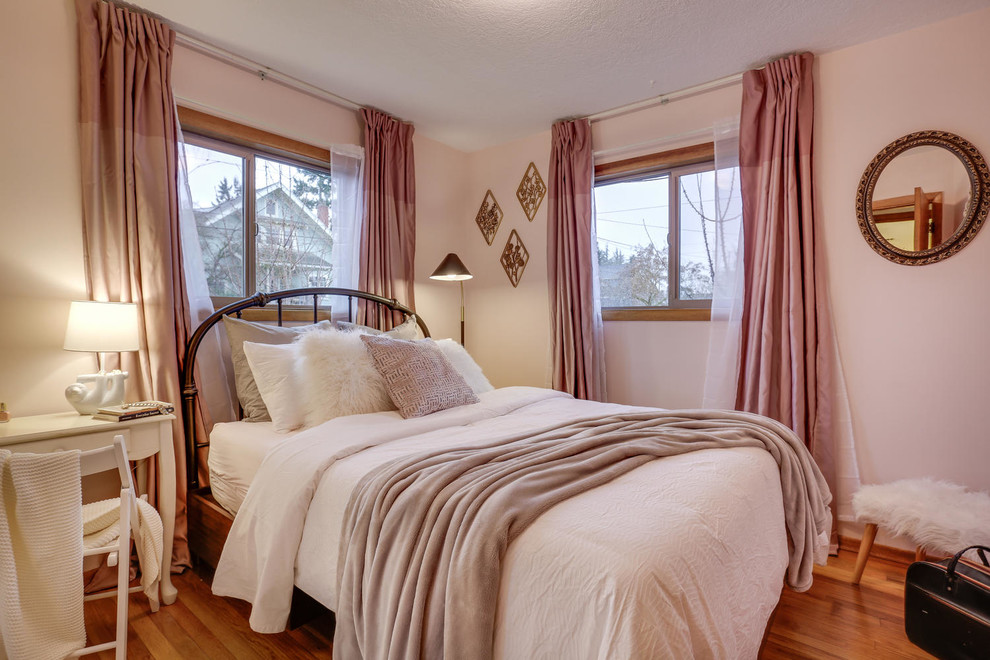 Imagen de dormitorio principal retro de tamaño medio con paredes rosas, suelo de madera en tonos medios y suelo marrón