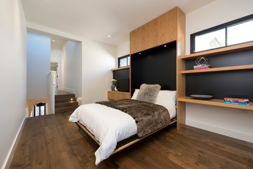 Cette photo montre une chambre d'amis tendance avec un mur blanc, un sol en bois brun et un sol marron.