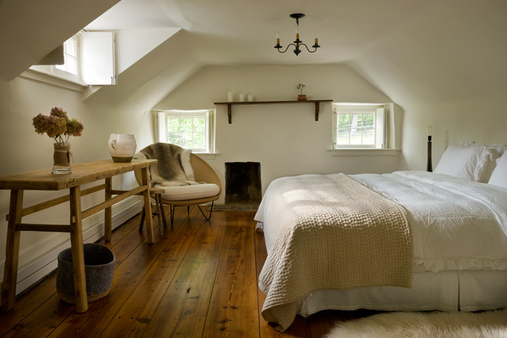 Imagen de dormitorio principal ecléctico de tamaño medio con paredes blancas, suelo de madera clara, todas las chimeneas y marco de chimenea de hormigón