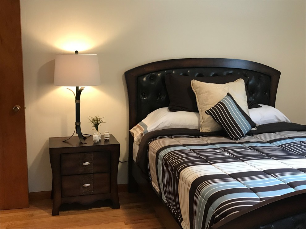 Medium sized traditional guest bedroom in New York with white walls, medium hardwood flooring, no fireplace and brown floors.