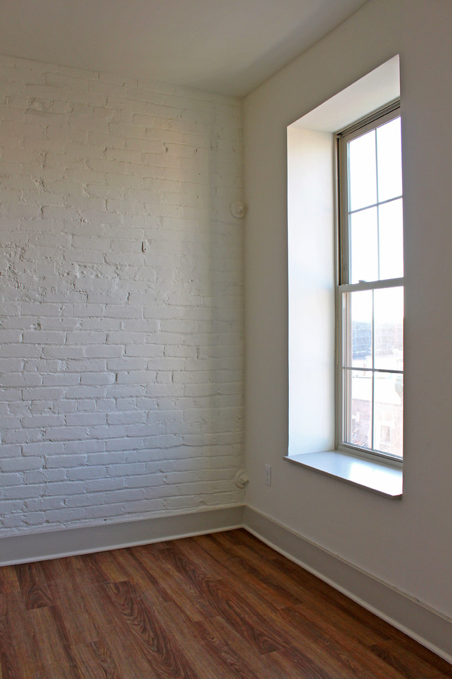 Modelo de habitación de invitados urbana pequeña con paredes blancas y suelo de madera en tonos medios