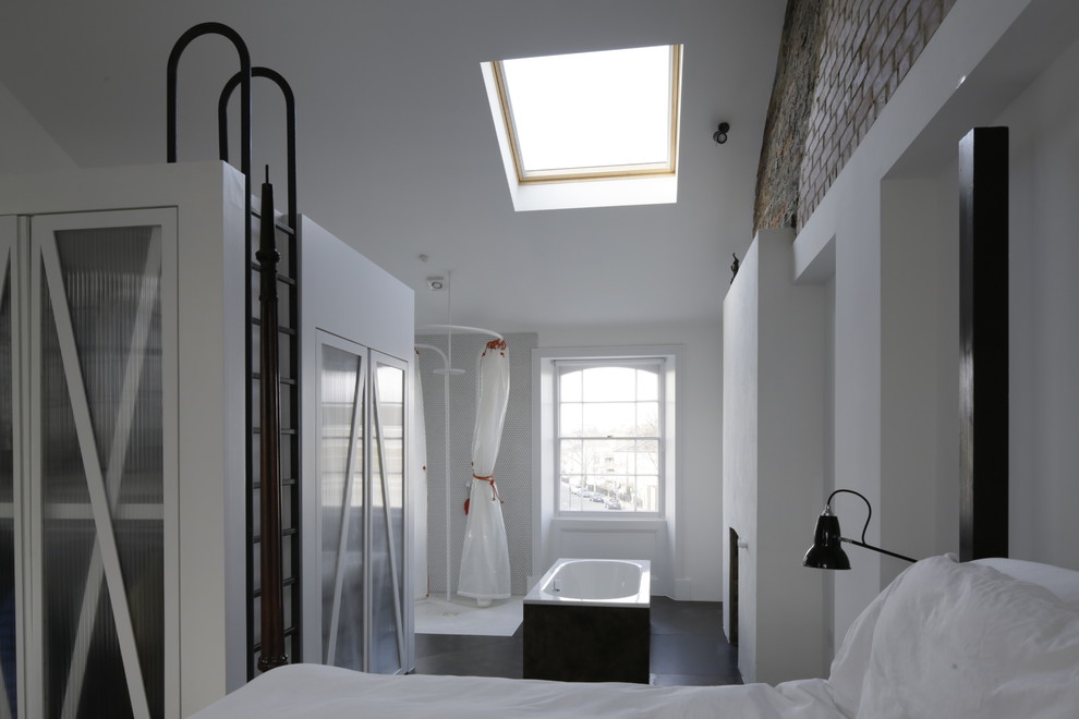 ロンドンにある広いコンテンポラリースタイルのおしゃれな主寝室 (白い壁、合板フローリング、標準型暖炉、漆喰の暖炉まわり、茶色い床) のインテリア