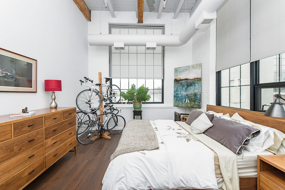 Foto de dormitorio industrial con paredes blancas, suelo de madera oscura y suelo marrón