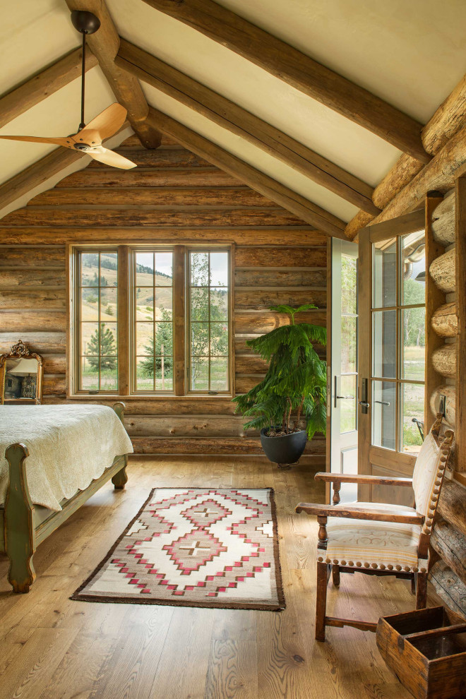 Uriges Schlafzimmer mit brauner Wandfarbe, braunem Holzboden, braunem Boden, freigelegten Dachbalken, gewölbter Decke und Holzwänden in Sonstige