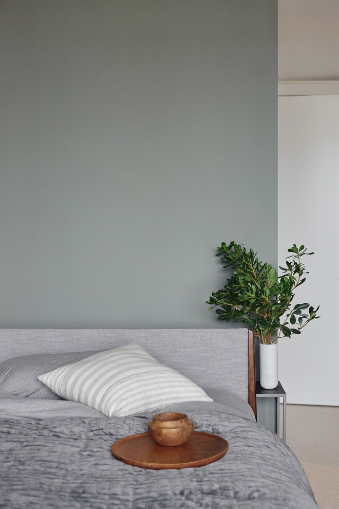Inredning av ett minimalistiskt mellanstort gästrum, med gröna väggar, heltäckningsmatta och beiget golv