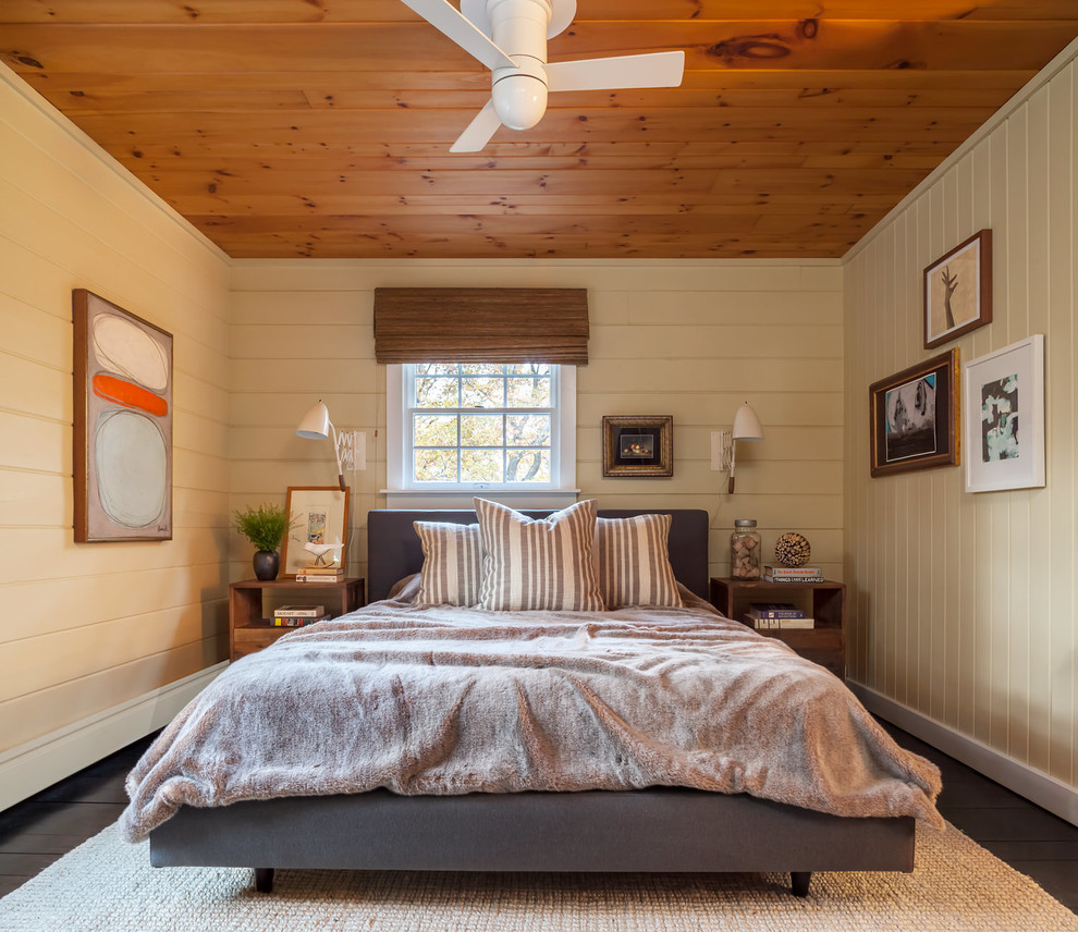 Imagen de dormitorio campestre con paredes amarillas, suelo de madera oscura y suelo marrón