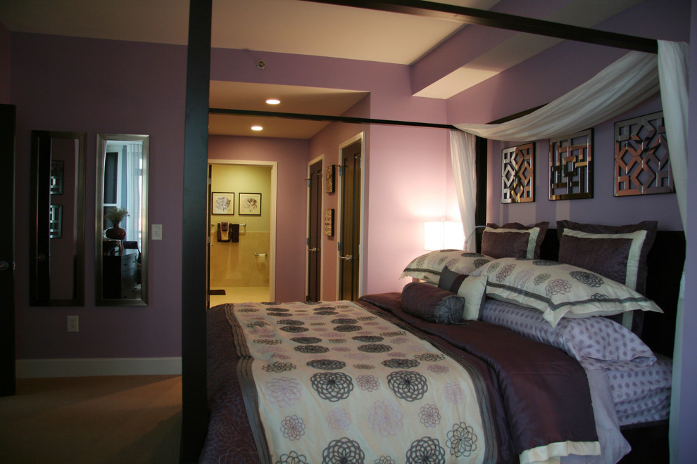 Modelo de dormitorio principal actual de tamaño medio con paredes púrpuras y moqueta