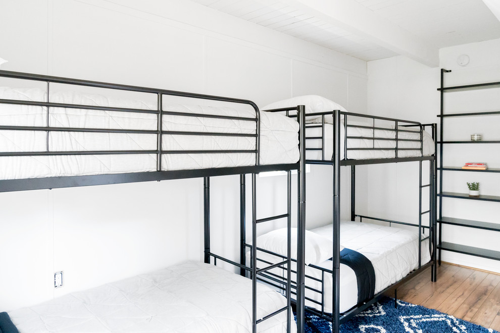 Ejemplo de habitación de invitados retro de tamaño medio sin chimenea con paredes blancas, suelo laminado y suelo marrón