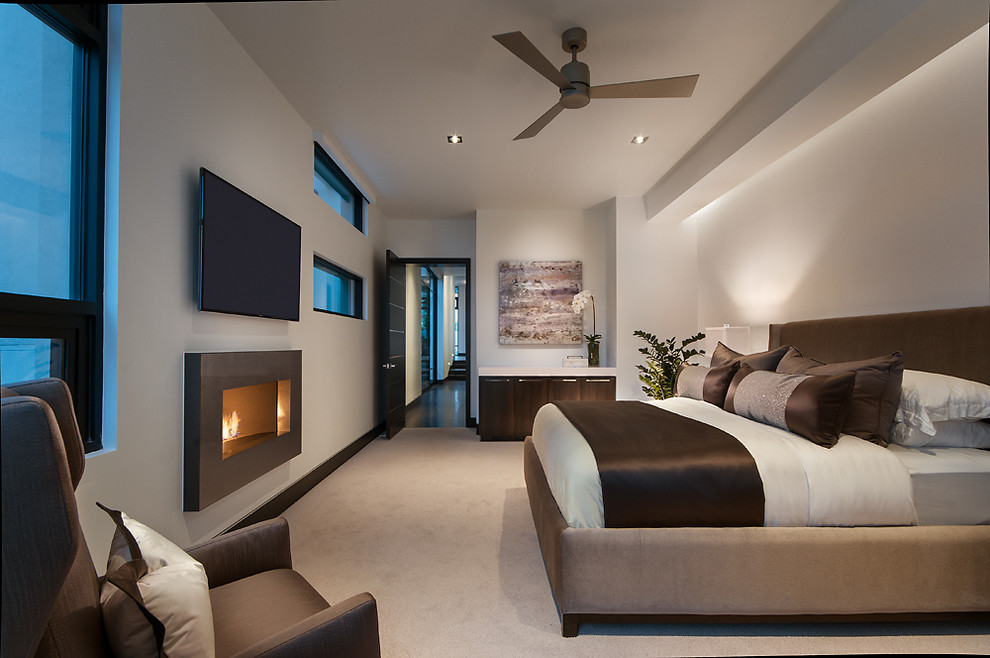 Modernes Schlafzimmer mit weißer Wandfarbe, Teppichboden und Gaskamin in Phoenix