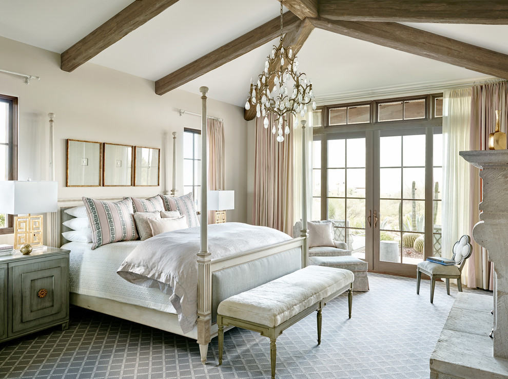 На фото: спальня в средиземноморском стиле с бежевыми стенами, ковровым покрытием и стандартным камином