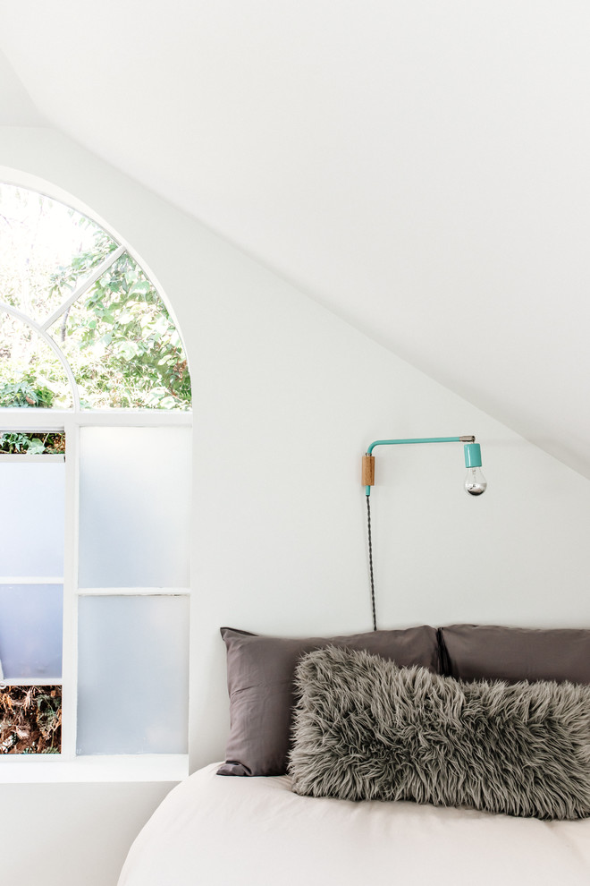 Ejemplo de dormitorio tipo loft minimalista grande sin chimenea con paredes blancas y suelo de madera clara
