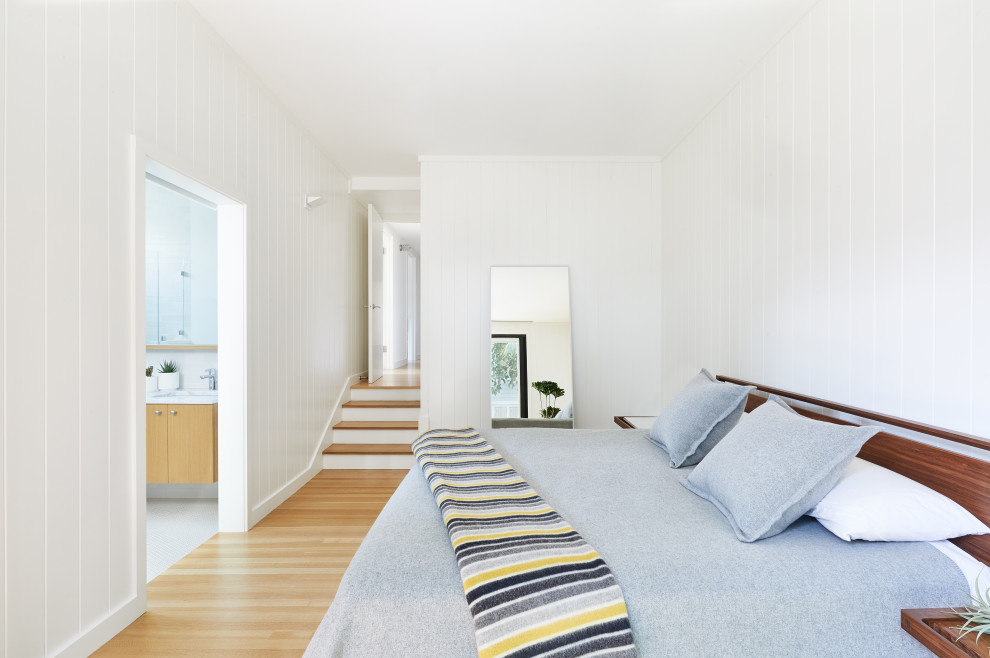 Idée de décoration pour une grande chambre parentale design avec parquet clair, un mur blanc, un sol beige et du lambris de bois.