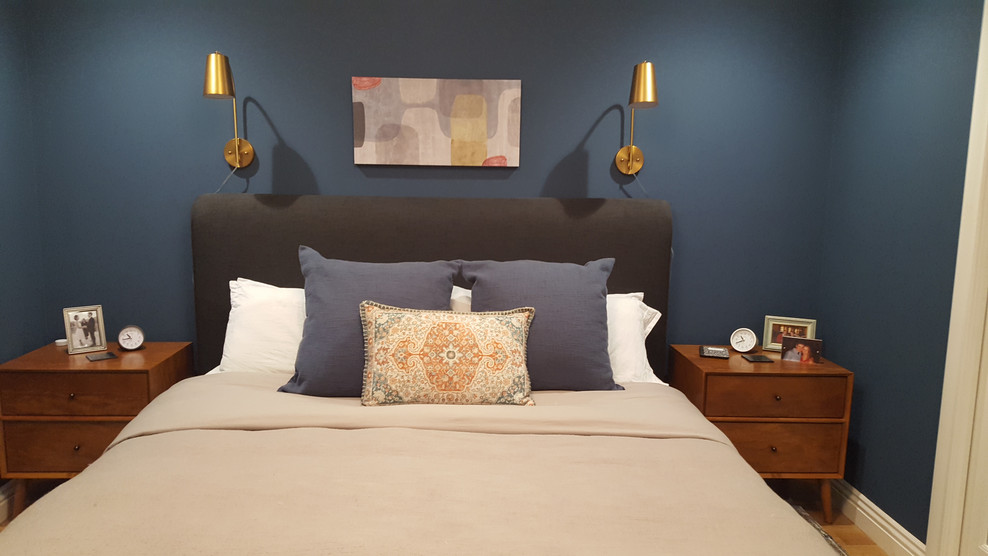 Modelo de dormitorio principal retro pequeño sin chimenea con paredes azules, suelo de madera en tonos medios y suelo marrón