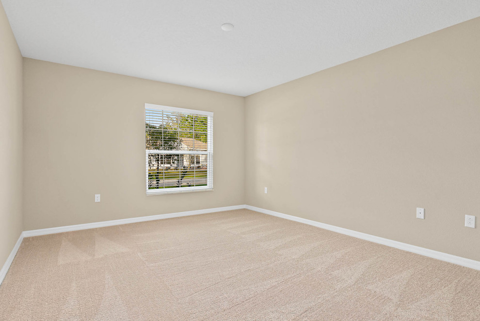 This is an example of a medium sized classic guest bedroom in Orlando with beige walls, carpet and beige floors.