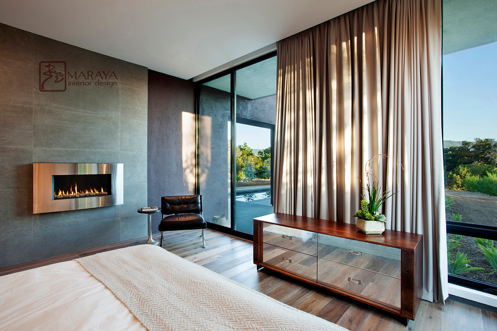 Mittelgroßes Modernes Hauptschlafzimmer mit grauer Wandfarbe, hellem Holzboden, Kamin und gefliester Kaminumrandung