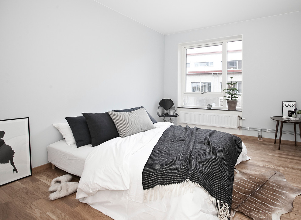 Design ideas for a medium sized scandinavian master bedroom in London with grey walls and light hardwood flooring.