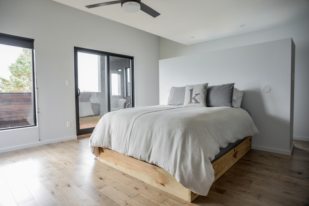 На фото: хозяйская спальня среднего размера в современном стиле с серыми стенами, светлым паркетным полом и коричневым полом без камина