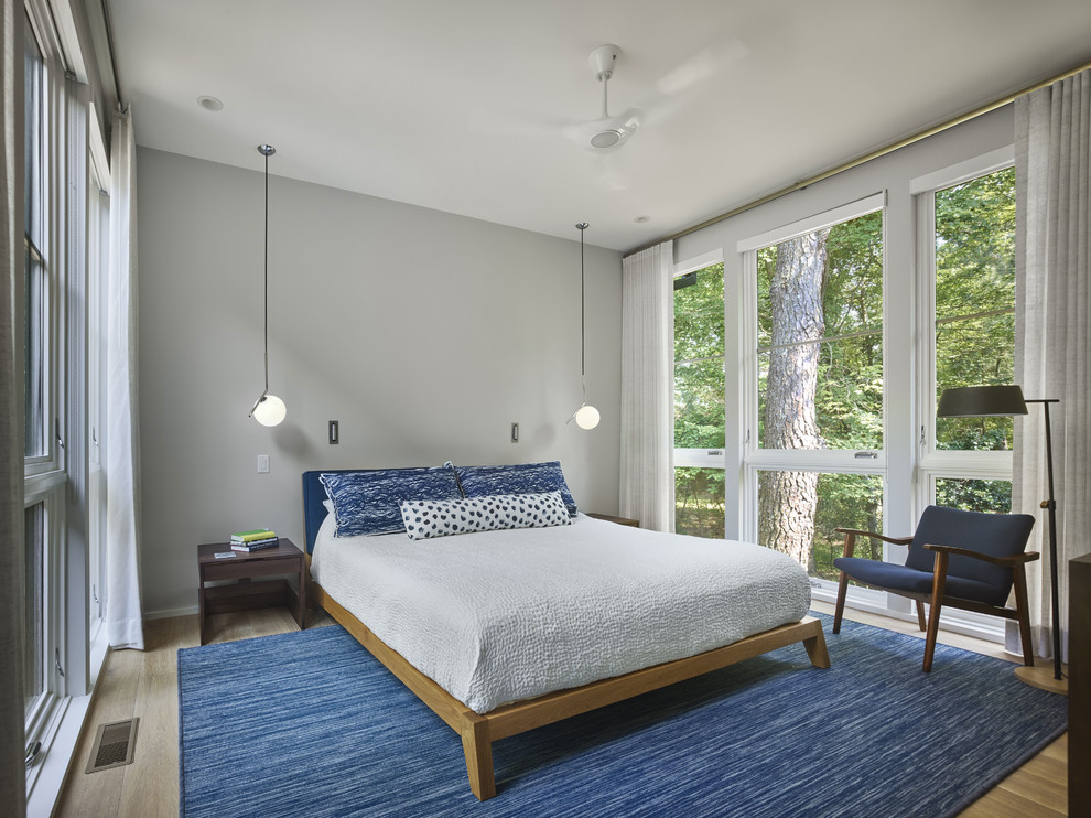 Kleines Modernes Hauptschlafzimmer ohne Kamin mit grauer Wandfarbe, hellem Holzboden und gelbem Boden in Sonstige
