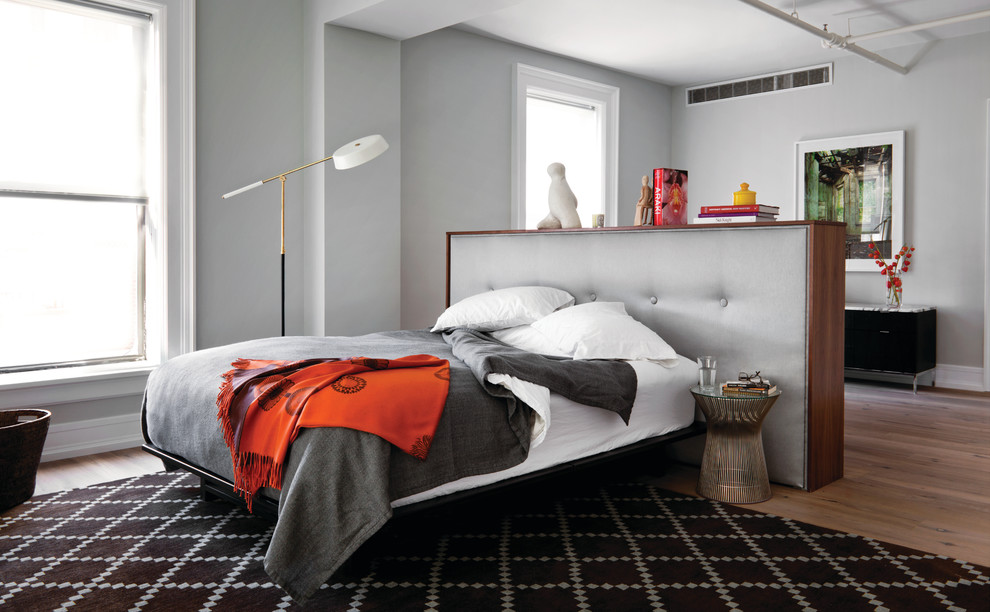 Стильный дизайн: серо-белая спальня в стиле лофт с серыми стенами и кроватью в нише - последний тренд