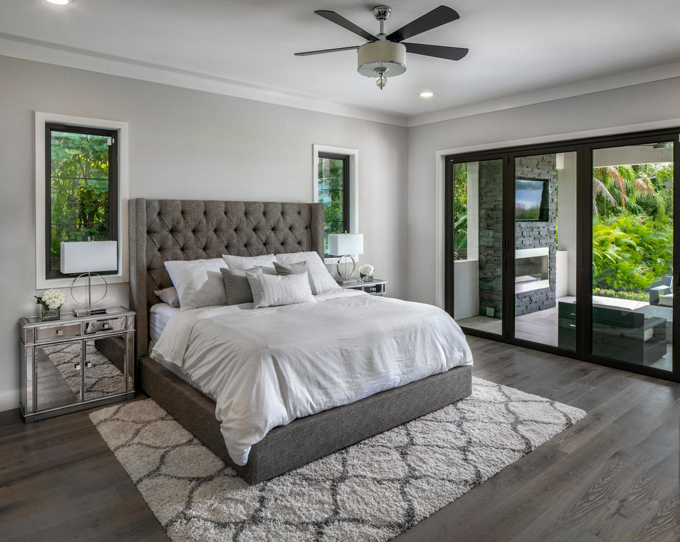 Cette image montre une grande chambre parentale grise et blanche minimaliste avec un sol en bois brun, un sol gris et un mur gris.