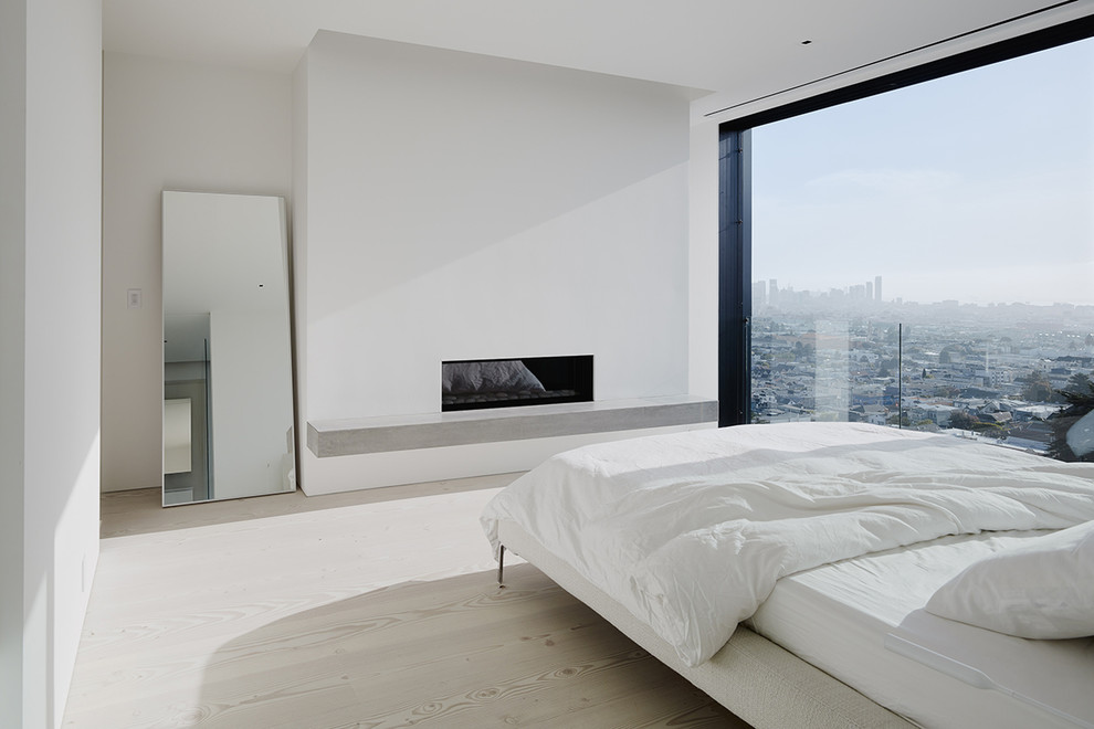 На фото: хозяйская спальня среднего размера в стиле модернизм с светлым паркетным полом, горизонтальным камином и фасадом камина из штукатурки с
